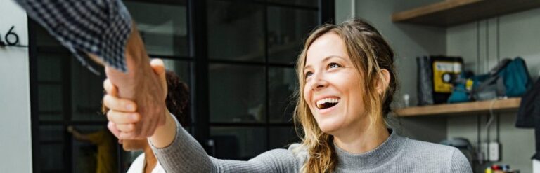 Woman smiling and shaking hands with her English trainer