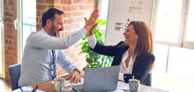 Business English Courses: Two happy business people high fiving after a successful business English course. / Zakelijk Engels cursussen.
