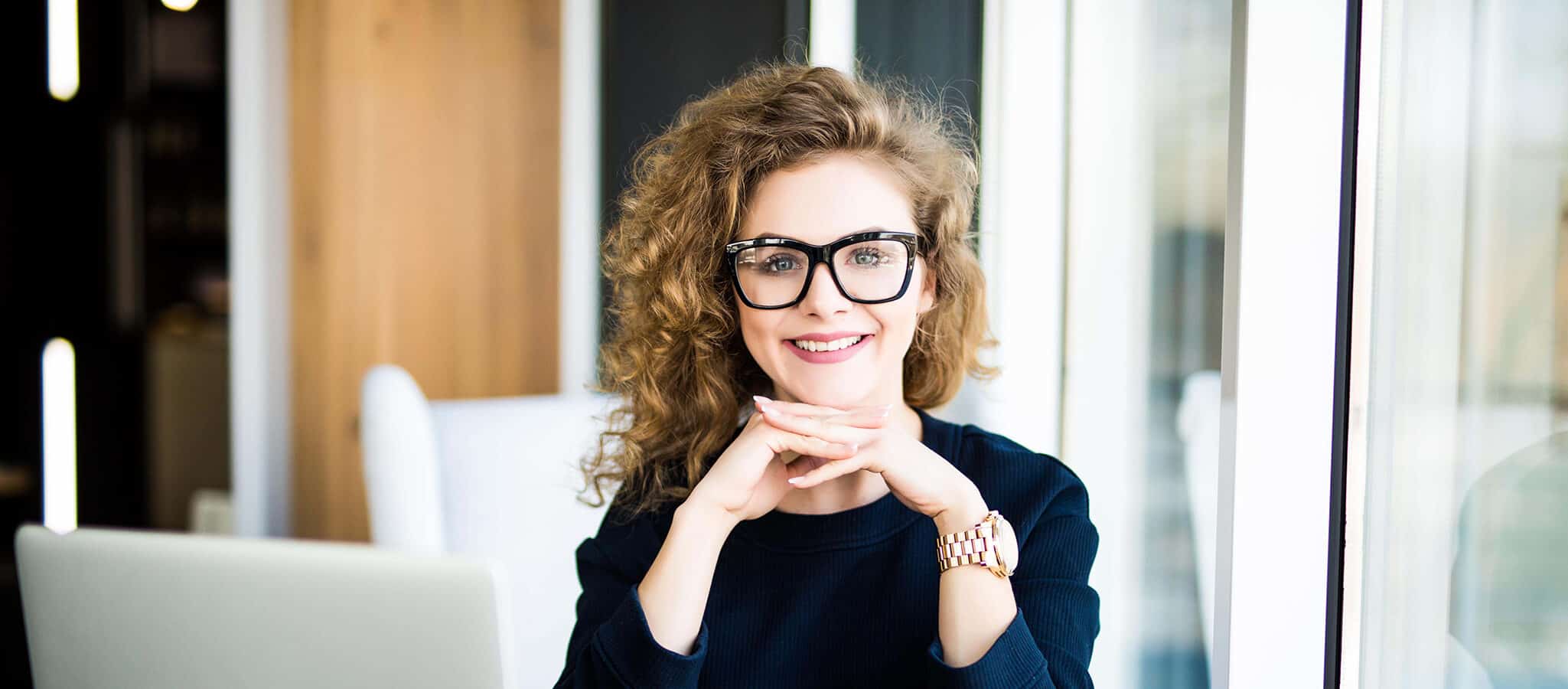 Intake teacher for English courses: Smiling woman with glasses and curly hair.