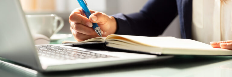 Close-up of a business woman's hand with a pen, writing